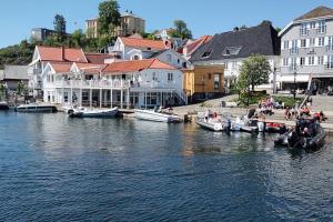 a group of boats docked in a river with buildings at Usjenert idyllisk Sjøbu in Kragerø +23 photos