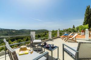 a patio with chairs and tables on a balcony at The Mountain Majesty in Skopelos Town