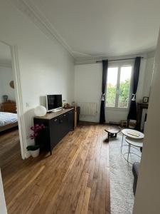 una sala de estar con suelo de madera y una habitación con cama en Happy Place - 15 min Paris & 30 min DisneyLand - Subways - Facilities - Free parking - Secured en Maisons-Alfort