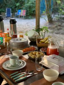a wooden table with plates and utensils on it at Pousada Bela Vista in Ilha do Mel +151 photos
