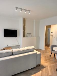 ein Wohnzimmer mit einem Sofa und einem Fernseher an der Wand in der Unterkunft Ostendeau - stijlvol appartement in hartje Oostende in Ostende