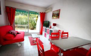 salon z czerwoną kanapą i stołem w obiekcie Villegiales Tee2 - En Rez de jardin dans une résidence avec piscine MAE-1154 w mieście La Grande-Motte