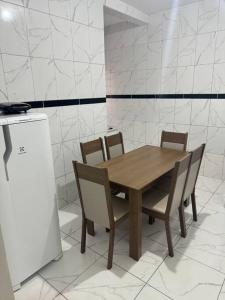 einem Holztisch mit vier Stühlen und einem Kühlschrank in der Unterkunft Casa Aconchego 6min basílica in Aparecida