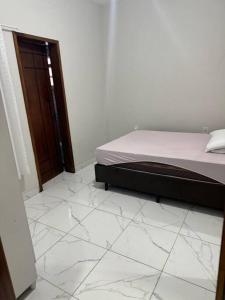ein Schlafzimmer mit einem Bett und einem gefliesten Boden in der Unterkunft Casa Aconchego 6min basílica in Aparecida