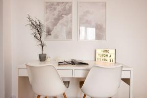 a table and two white chairs in a room at White Heaven - Stylish 9th Floor Apartment with Views in Bucharest +23 photos