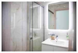 un bagno bianco con lavandino e doccia di Ammoshine Apartment a Néa Péramos Altre 20 foto