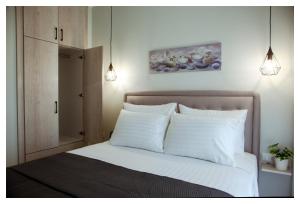 a bedroom with a bed with white sheets and pillows at Ammoshine Apartment in Nea Peramos