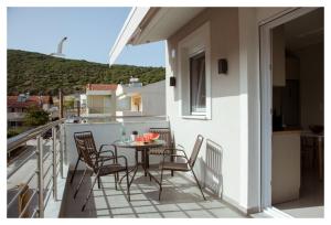 a small balcony with a table and chairs on it at Ammoshine Apartment in Nea Peramos