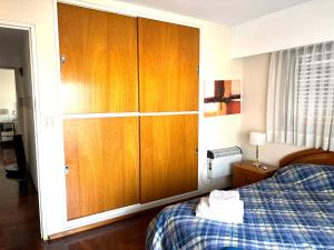 a bedroom with a bed and wooden cabinets at Céntrico y amplio departamento en La Cañada in Cordoba