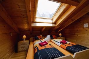 Cette chambre en bois dispose de 2 lits et d'une fenêtre. dans l'établissement Chalet Regenbogen Leukerbad mit Indoorrutschbahn, à Loèche-les-Bains