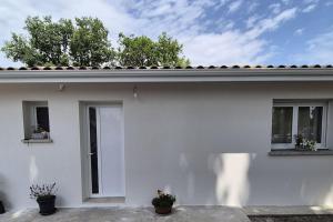 a white house with two windows and two potted plants at Casa Del Sole in Soussans