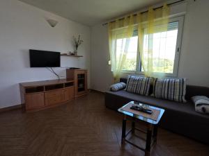a living room with a couch and a flat screen tv at Apartmani Daniela in Rab