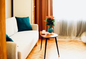 a living room with a couch and a vase with flowers on a table at Stanislawa Augusta by P&J Apartments in Warsaw