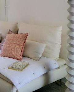 Un sofá blanco con almohadas y una bandeja. en Maison Castaings, en Lucq-de-Béarn