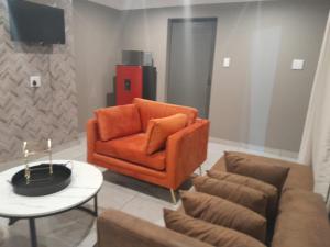 a living room with an orange chair and a table at Bokmakierie in Centurion