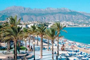 a beach with palm trees and chairs and the ocean at Villa Panoramica / La Nucia (Costa Blanca) in La Nucía
