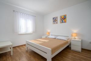 a white bedroom with a bed and a window at App D Comfort in Umag