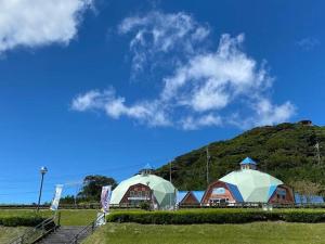 two domes and a building with a hill in the background at Agriland E, a village of dreams, wind and music - Vacation STAY 88882v in Ibusuki