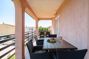 a table and chairs on a balcony with a bowl of fruit at App D Comfort in Umag