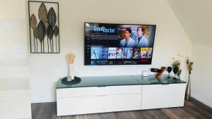 a living room with a tv on a white wall at HARMONY "2" stylishes 2 Zimmer Apartment 1 OG Balkon Garten Parkplatz in Gütersloh
