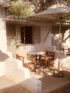 a patio with a table and chairs and an umbrella at Barreira Beachfront Rooms 6 in Kalamata +7 photos