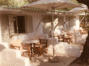 a group of tables and chairs under an umbrella at Barreira Beachfront Rooms 6 in Kalamata