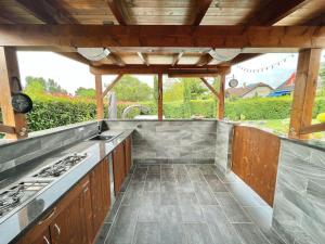 an outdoor kitchen with wooden cabinets and a stove at Tünde NENE Apartman in Zánka