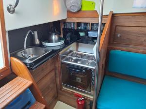 Una pequeña cocina con fregadero y estufa. en Jacht w Marinie Jastarnia, en Jastarnia