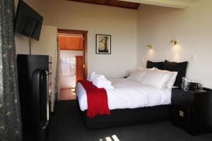 Habitación de hotel con cama con manta roja en Te Puru Beach Lodge en Te Puru