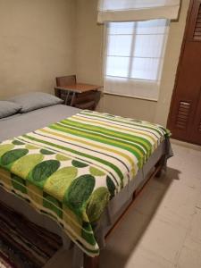 1 dormitorio con 1 cama con edredón verde y blanco en Departamento a un paso del Metropolitano y Miraflores en Lima