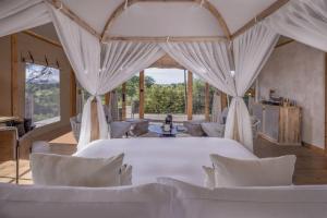 a room with a bed and chairs and windows at JW Marriott Masai Mara Lodge in Masai Mara +154 photos