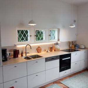 - une cuisine avec des placards blancs, un évier et 2 fenêtres dans l'établissement Landhaus Ottenberg, à Kressbronn am Bodensee