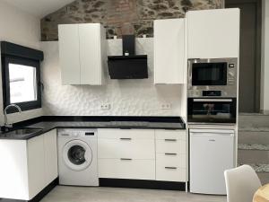 a kitchen with white cabinets and a washer and a microwave at CASA SANTI Y LAURA in Cudillero
