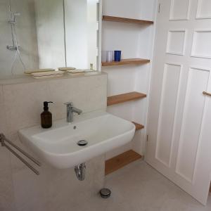 une salle de bain avec un lavabo blanc et un miroir dans l'établissement Landhaus Ottenberg, à Kressbronn am Bodensee