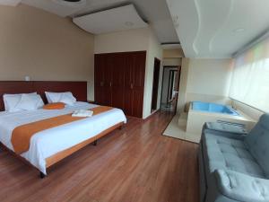 a bedroom with a bed and a couch and a tub at Hotel Xilon Pasto in Pasto