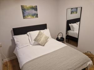 a bedroom with a bed with white sheets and a mirror at Green Isle in Kenmare