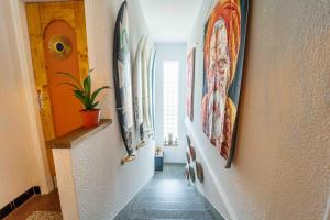 a hallway with paintings on the walls of a house at La Boga L'Auberge à l'ambiance Surf à Biscarrosse Plage in Biscarrosse-Plage