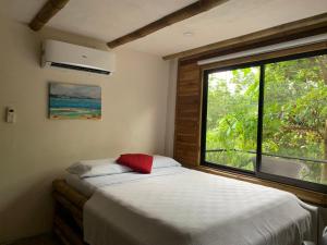 a bedroom with a bed and a large window at Bambura Hermosa villas in Uvita