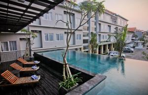 a swimming pool with two chairs and a building at The Salak Style Hotel in Denpasar