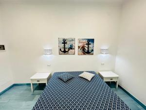 a bedroom with a bed with two tables and two posters at Sky Ponza - Immobilevante in Ponza