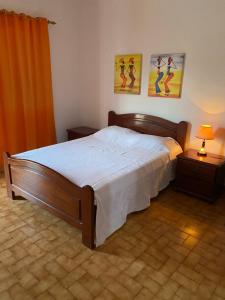 una camera da letto con un grande letto e due quadri alle pareti di Muralha Rooms a Mindelo