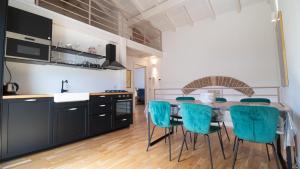 a kitchen with a table and blue chairs at Corte Coronardi - Elegante casa Campidanese in Quartu SantʼElena