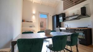 a kitchen with a table and some green chairs at Corte Coronardi - Elegante casa Campidanese in Quartu SantʼElena +20 photos