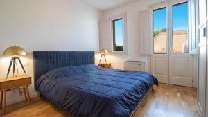 a bedroom with a bed with a blue comforter and two lamps at Corte Coronardi - Elegante casa Campidanese in Quartu SantʼElena