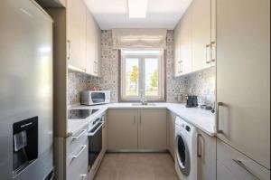 a kitchen with white cabinets and a window at Casa Peixinha in Aveiro