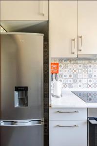 una nevera de acero inoxidable en una cocina con armarios blancos en Casa Peixinha en Aveiro