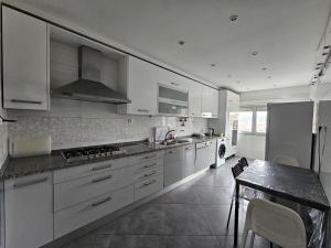 a kitchen with white cabinets and a table in it at Odivelas Inn in Odivelas