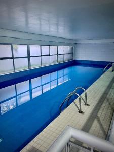 a large swimming pool with blue water and windows at Appartement avec piscine in Paris