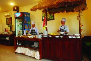 two chefs standing behind a counter in a kitchen at Hau Giang Hotel in Can Tho