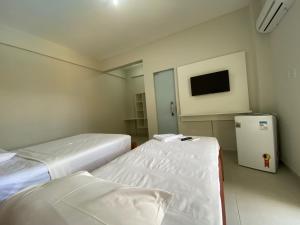 a hospital room with two beds and a tv at Guará Praia Hotel in Salinópolis